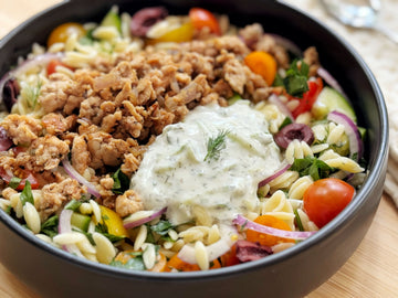 Salad with ground meat, vegetables, and a dollop of sauce in a black bowl.